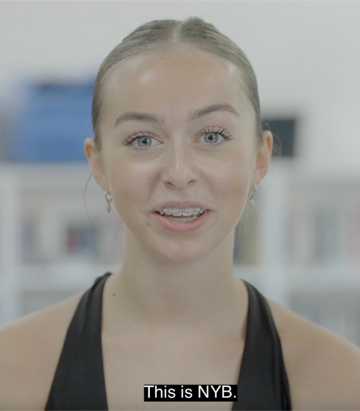 Youth Ballet member is on camera, subtitles read: This is NYB